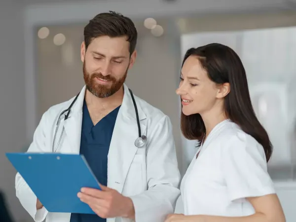 Médico y profesional sanitaria revisando juntos una carpeta con documentación clínica
